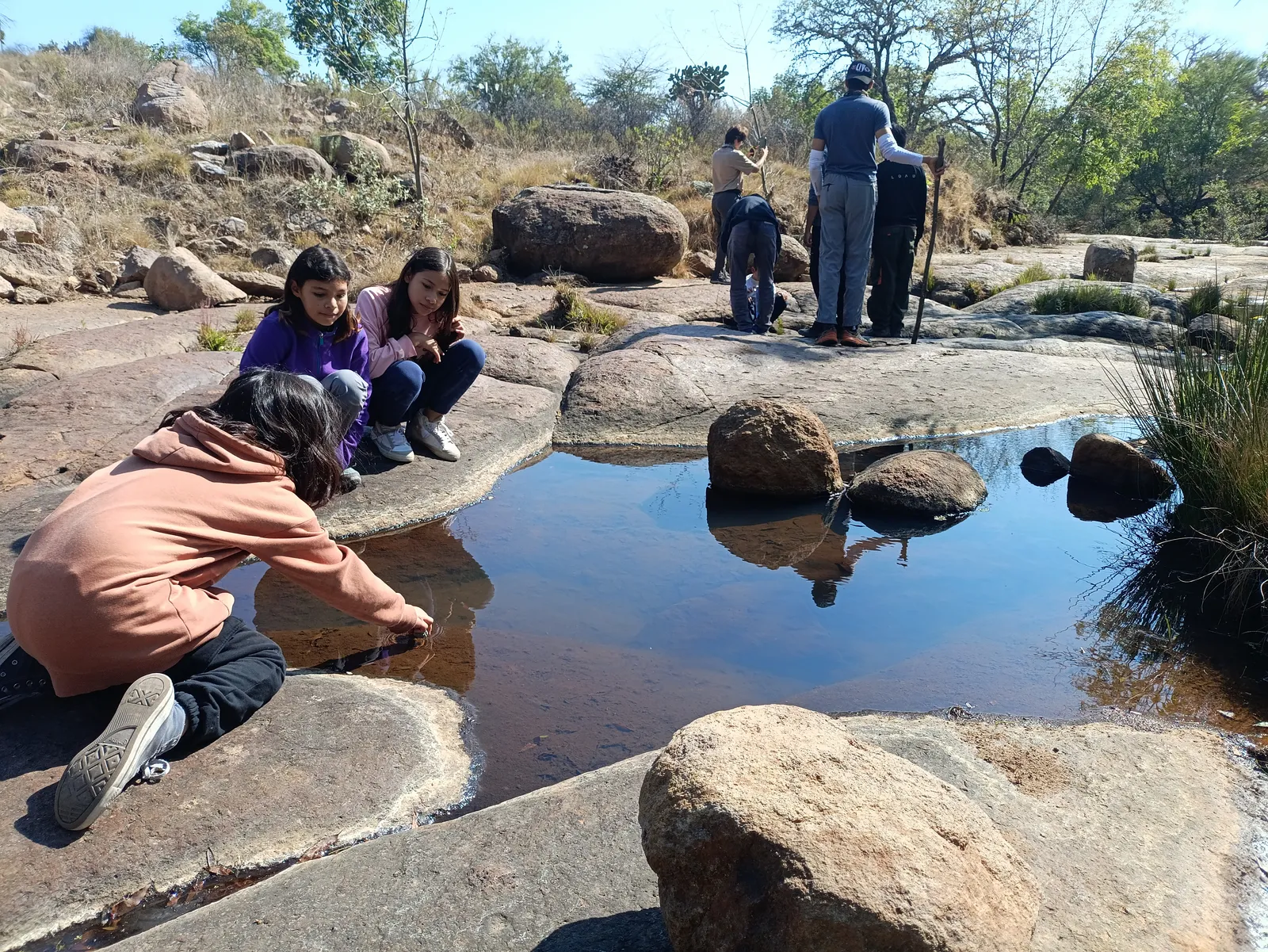 Familias explorando una poza de agua entre rocas en Manantial y Presa del Rayo, Huimilpan.