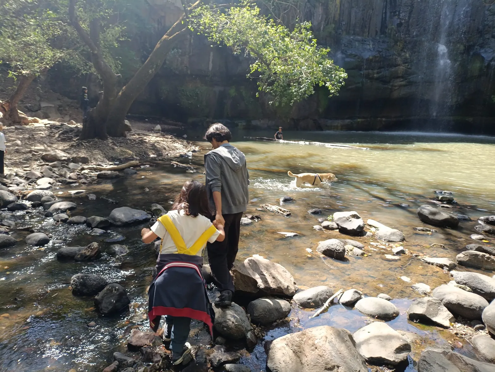 Familia y mascota recorriendo la poza de agua bajo la Cascada de Tixhiñú, Aculco.