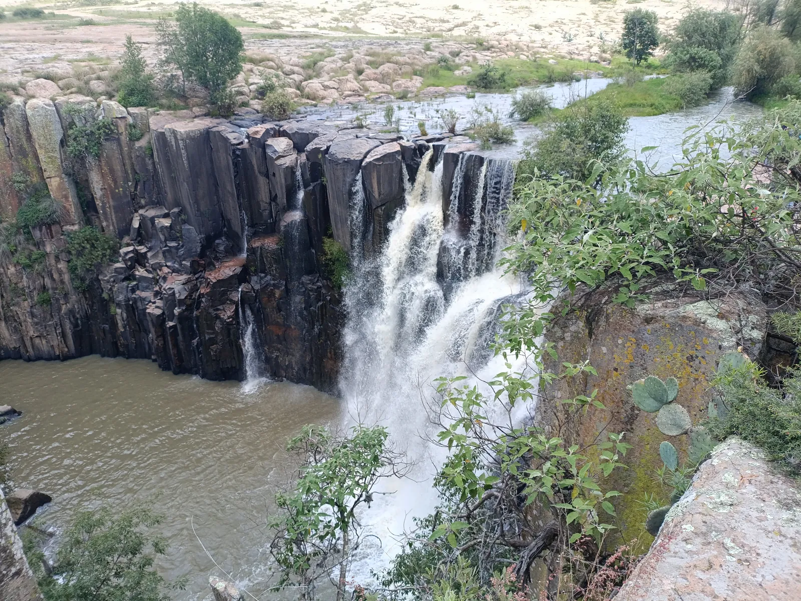 Vista de la Cascada de la Concepción en Amealco, Querétaro, entre formaciones rocosas y vegetación.