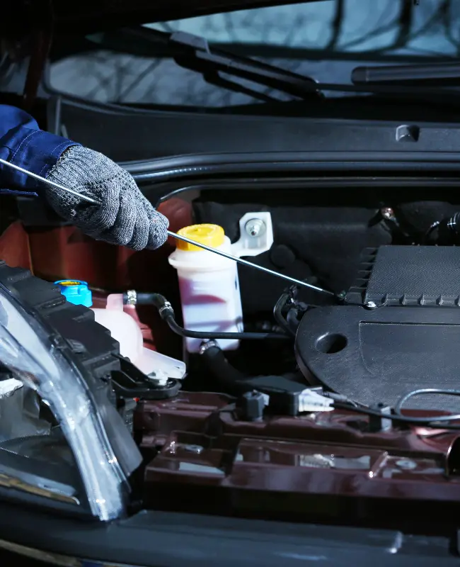 Gloved man checking the oil on a motor vehicle