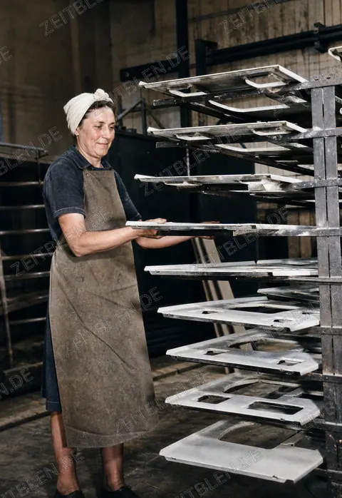 Arbeiterin an aufgehängten Herdbauteilen bei Wamsler