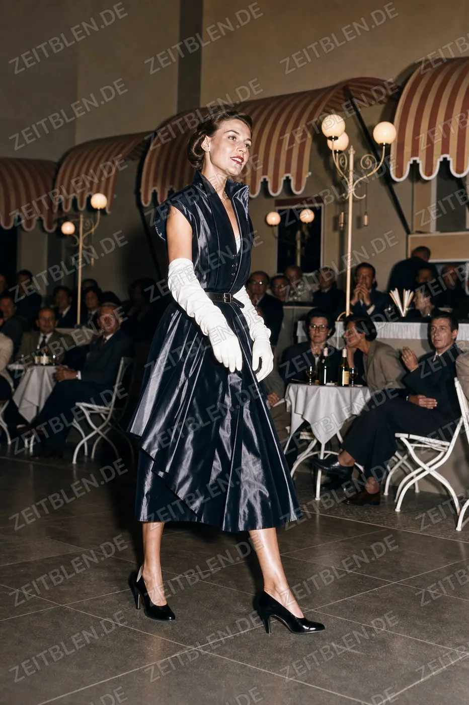 Mannequin im glänzenden Cocktailkleid bei der Modeschau „Elegante Welt“