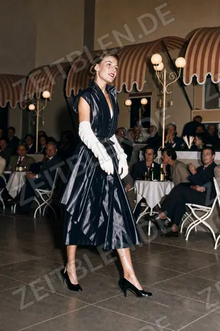 Mannequin im glänzenden Cocktailkleid bei der Modeschau „Elegante Welt“
