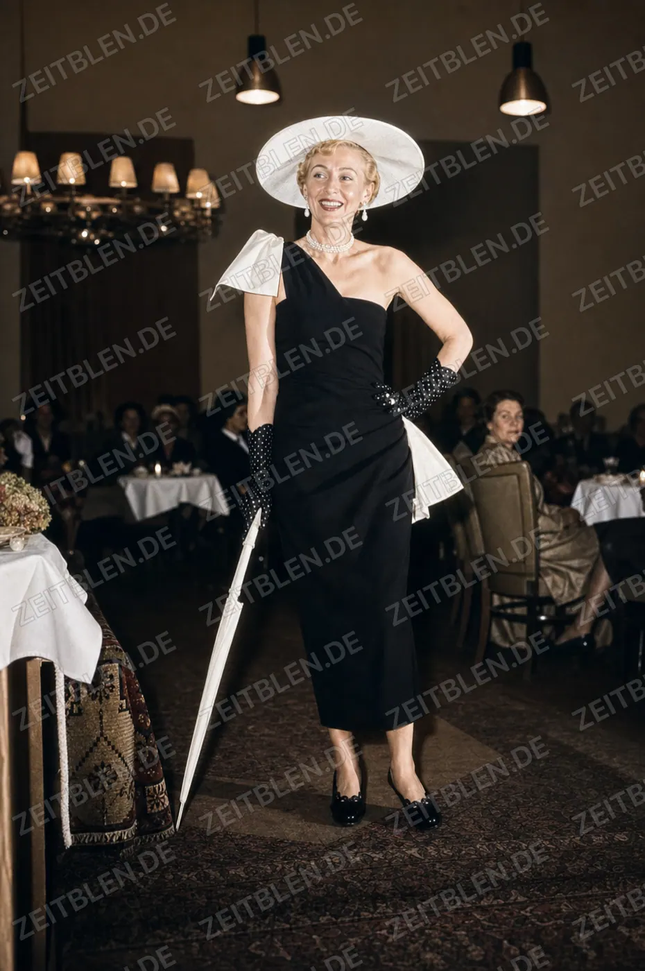 Dunkles Kleid mit breitem Hut und Sonnenschirm