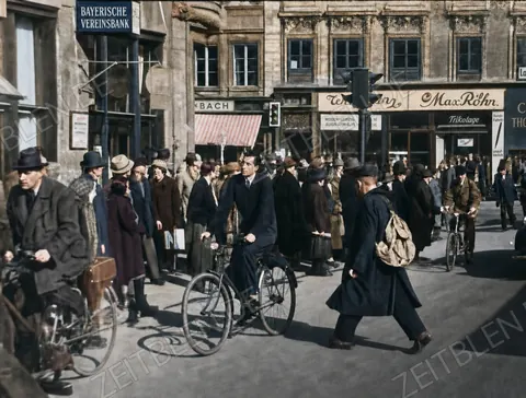 Belebter Münchner Straßenverkehr vor Geschäftshäusern
