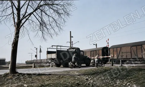 Lastwagen wartet am Bahnübergang vor einem Güterzug