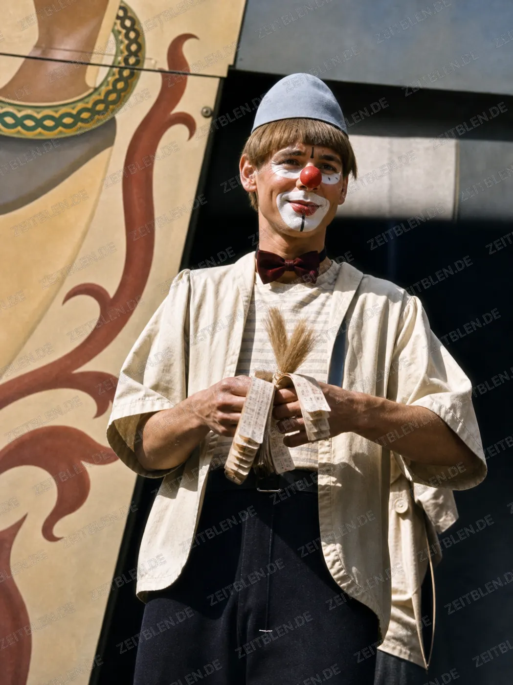Clownhafter Schausteller vor einer Revuekulisse