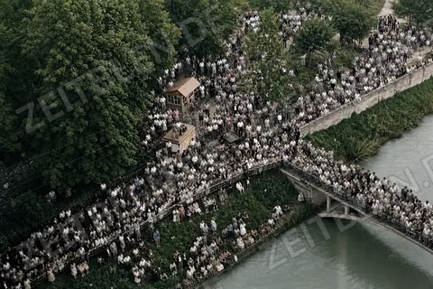 Große Menschenmenge an der Isar mit Fußbrücke