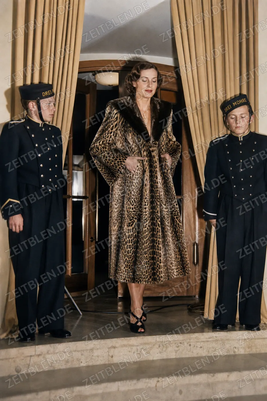 Model im Leopardenmantel mit Hotelpagen im Hotel Drei Mohren