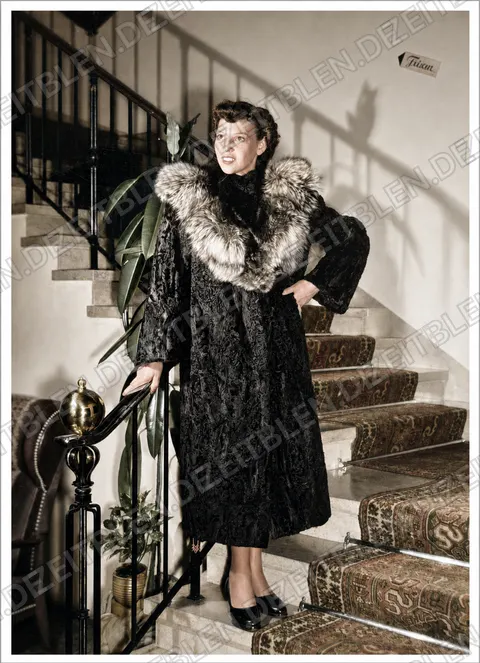 Model mit hellem Pelzkragen auf der Hoteltreppe