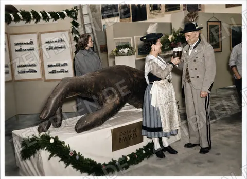 Trachtenpaar am Löwenexponat der Bavaria-Ausstellung