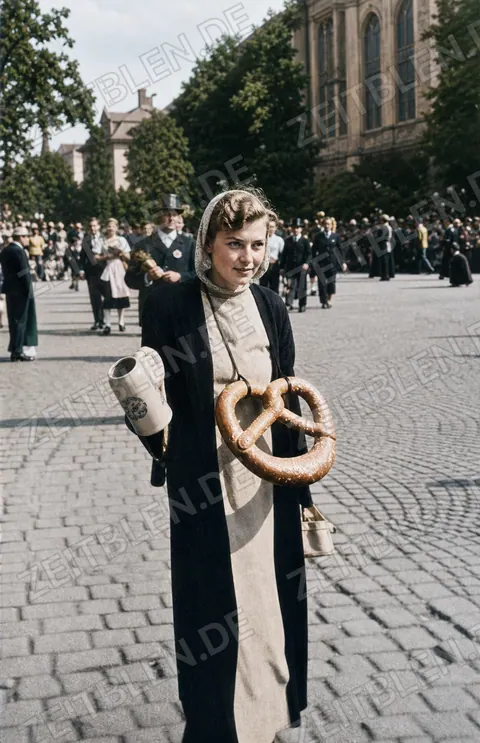 Kostümierter Teilnehmer mit Brezn beim Trachtenzug 1949