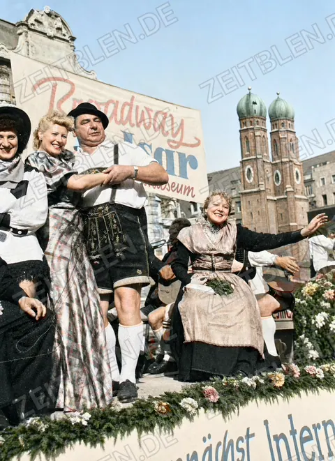 Kostümierter Festwagen mit Münchner Kulisse