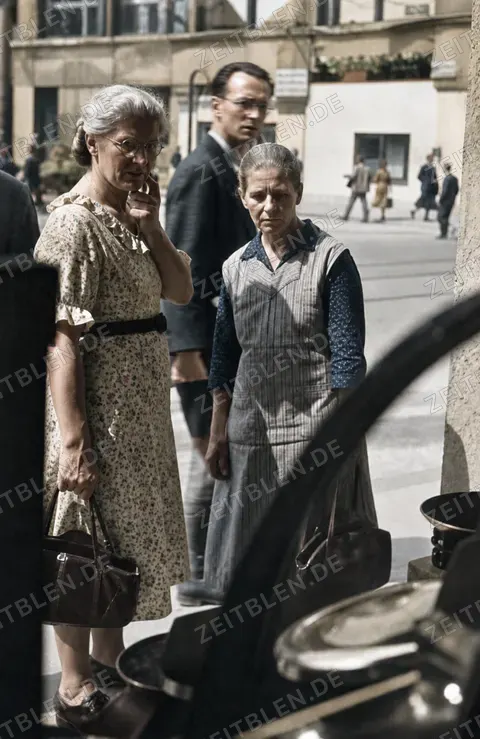 Passanten und zwei Frauen vor einem Münchner Schaufenster