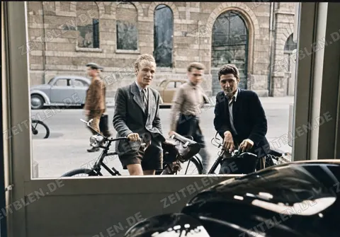 Zwei Radfahrer vor einer Münchner Ladenfront mit Automobil