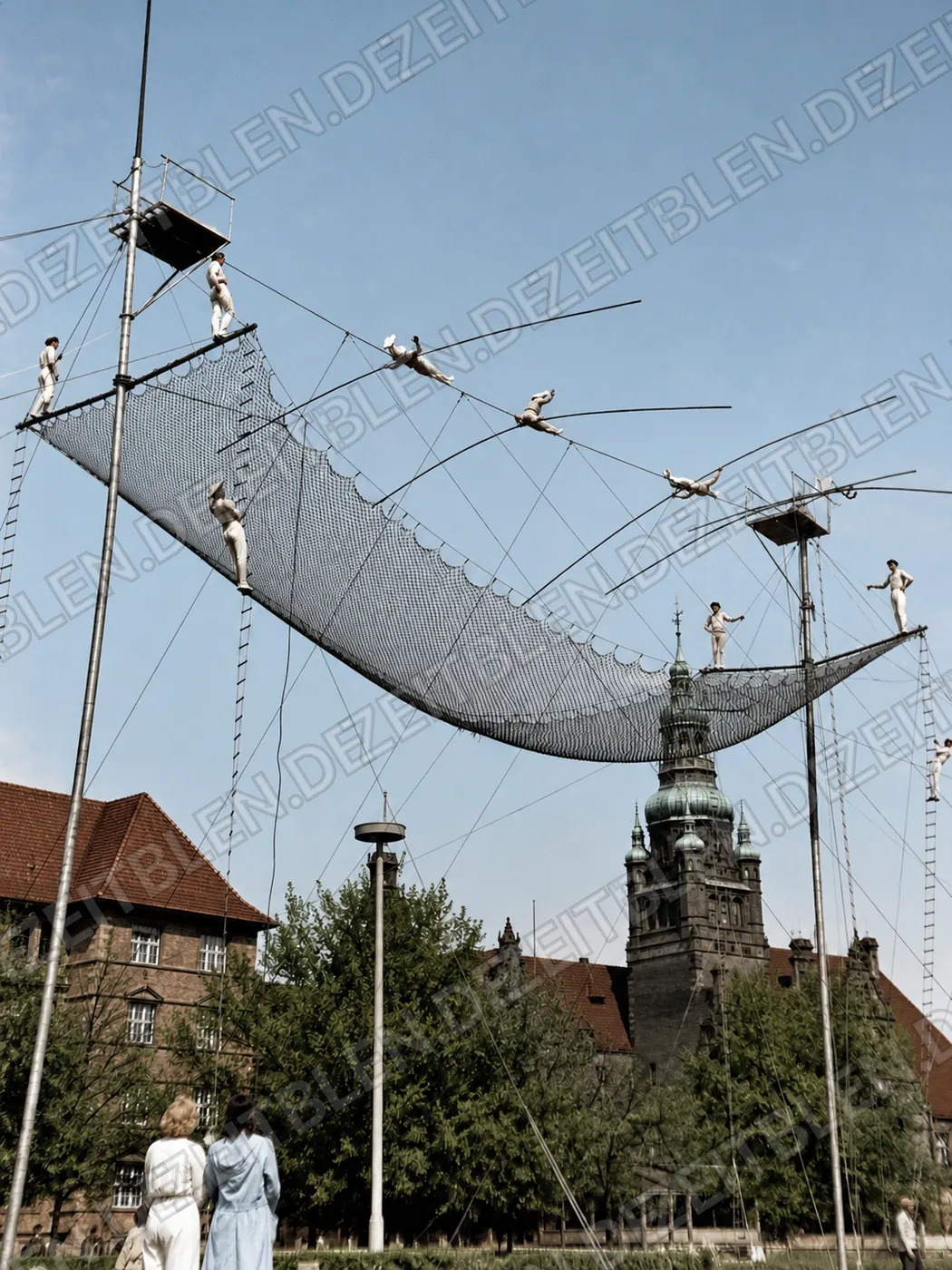Mehrere Hochseilartisten ueber einem Fangnetz