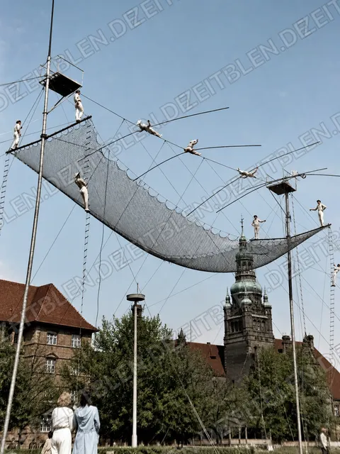 Mehrere Hochseilartisten ueber einem Fangnetz
