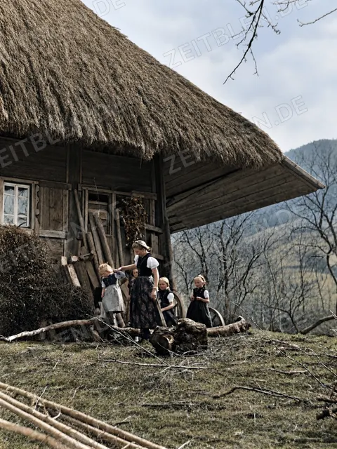 Kinder und Erwachsene an einem Bauernhof in den 1930er Jahren