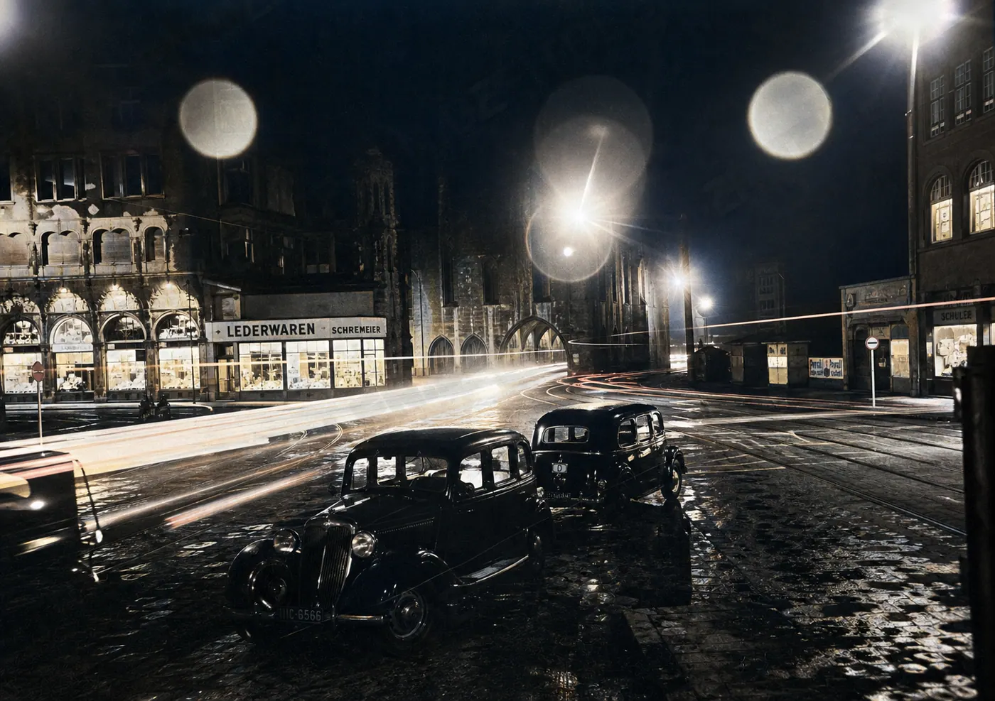 Nächtliche Münchner Straße mit Tramgleisen und Lichtspuren