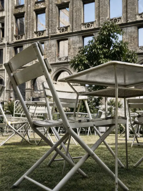Cafémöbel vor kriegsbeschädigter Fassade in München