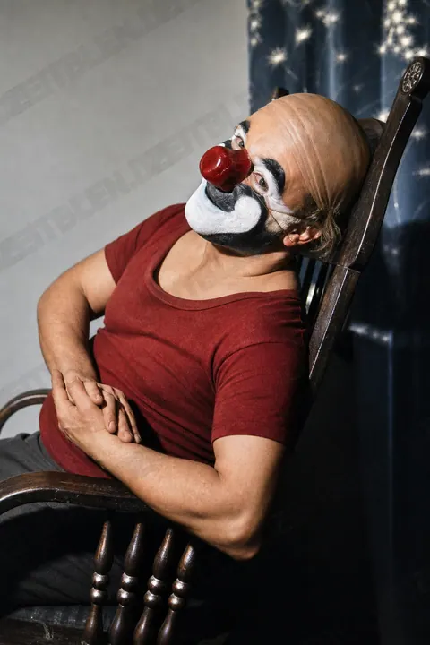 Charly Rivel sitzend in Clownschminke