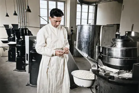 Mitarbeiter kontrolliert Tabletten an einer Produktionsmaschine der Trineral-Werke, München, 10. März 1949