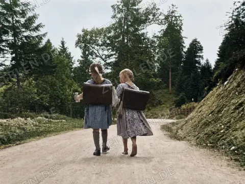 Schülerinnen mit Ranzen auf einer Waldstraße