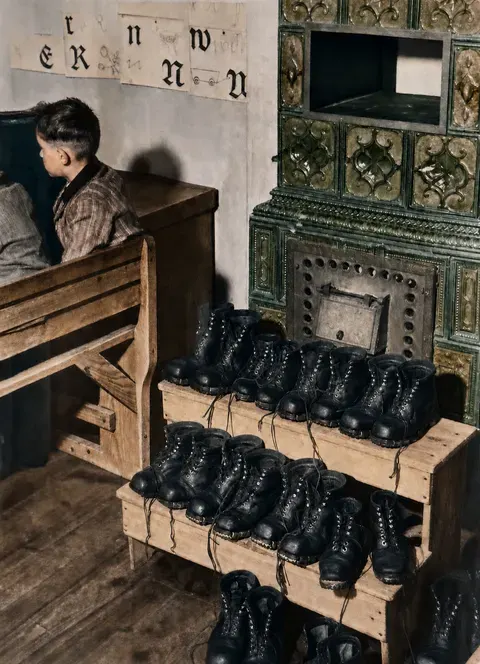 Winterschuhe am Kachelofen einer Dorfschule, 1936
