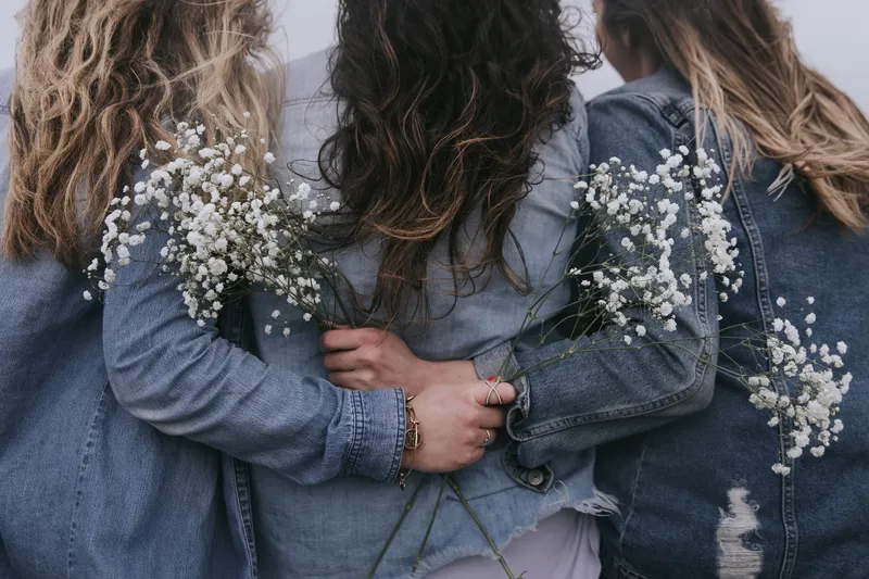 Close-up of a group of friends getting their permanent jewelry fitted by a professional