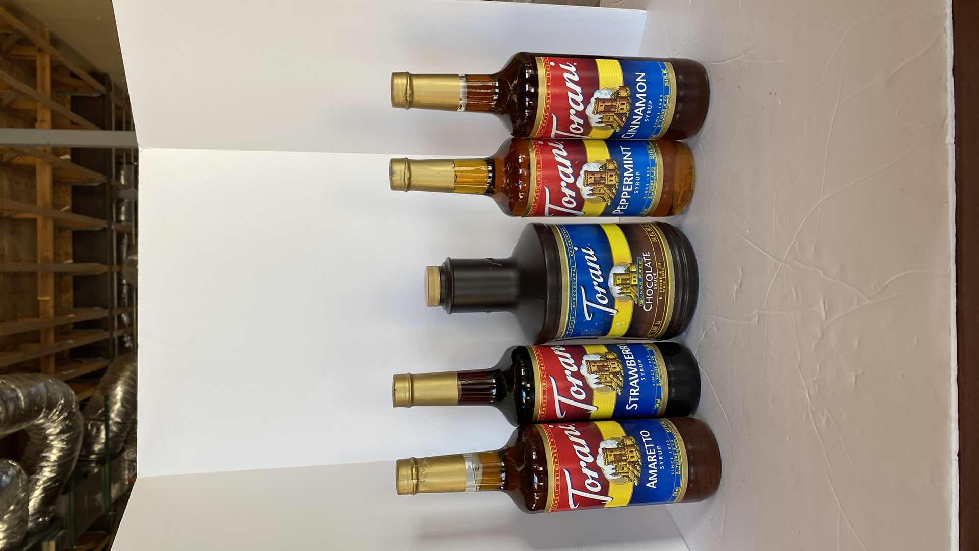 Photo 1 of TORANI CHOCOLATE SAUCE AND 4 SYRUPS UNKNOWN EXPIRATION DATES, INCLUDES TOTE