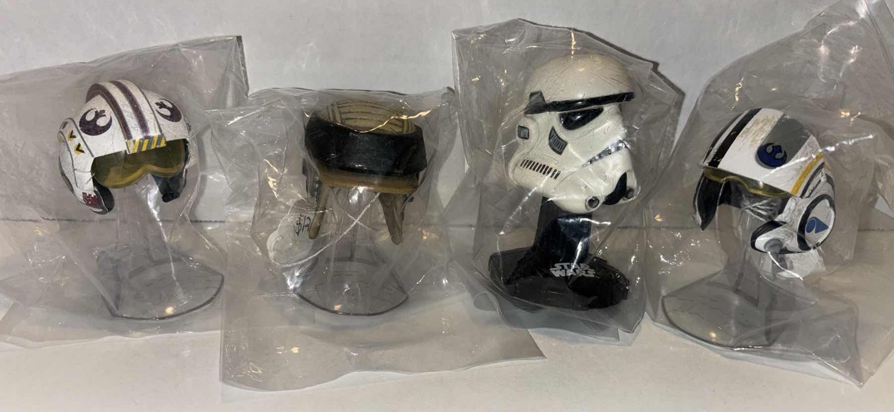 Photo 1 of STAR WARS THE BLACK SERIES 4 PC TITANIUM SERIES DIE CAST MINI HELMETS W STANDS (LUKE SKYWALKER TIE FIGHTER PILOT, REBEL COMMANDO, STORMTROOPER, POE DAMERON)