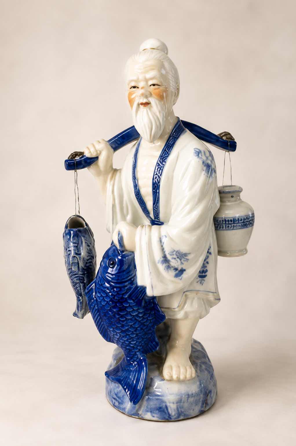 Photo 1 of VINTAGE BLUE & WHITE ASIAN PORCELAIN FISHERMAN FIGURINE DETAILED HAND-PAINTED FIGURE WITH FISH & HANGING VESSEL ESTIMATED RETAIL VALUE:$125 H16”