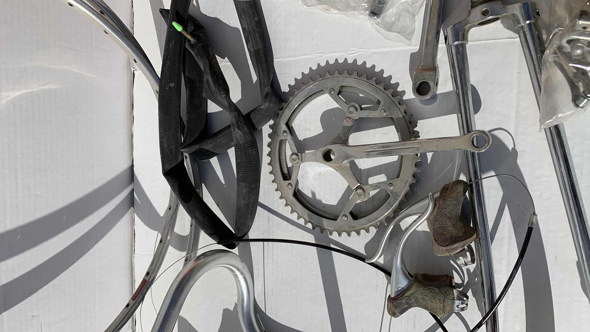 Photo 1 of ASSORTED BICYCLE PARTS AND ACCESSORIES, TO INCLUDE GEARS, BIKES SHOES SIZED 10, HANDLE BARS, RIM AND TIRE TUBES.