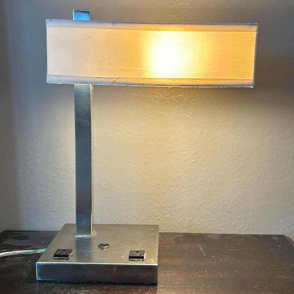 Photo 1 of SLEEK, MODERN CHROME TABLE LAMP STANDING 19 INCHES TALL, FEATURING BUILT-IN PLUG-INS FOR BOTH CELL PHONES AND LAPTOPS.