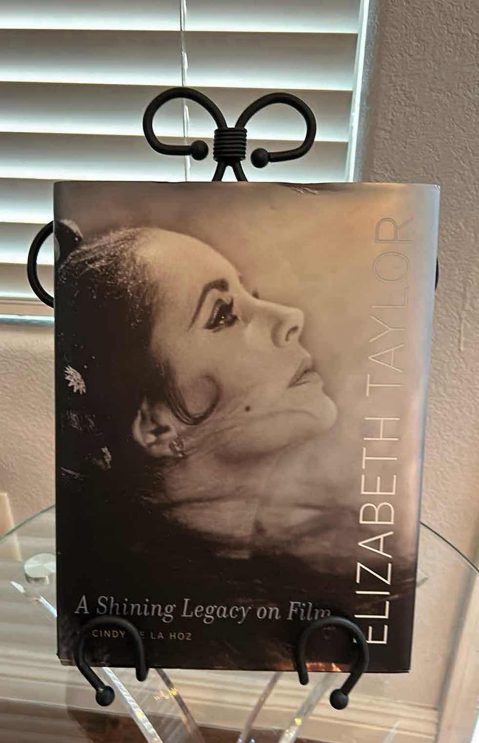 Photo 1 of HARDCOVER, COFFEE TABLE BOOK, ELIZABETH TAYLOR, A SHINING LEGACY ON FILM, AND METAL BOOK STAND.