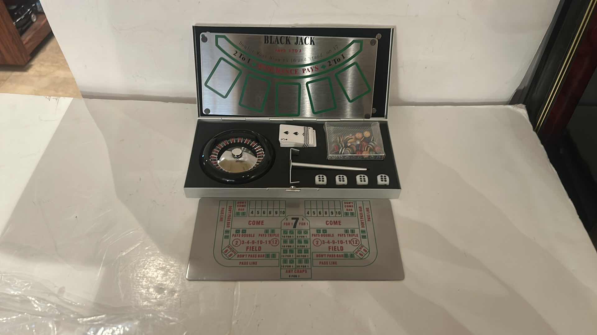 Photo 1 of MINIATURE GAMBLING SET IN METAL BOX, INCLUDING ROULETTE, CRAPS, AND BLACKJACK. 9” x H4 1/4”