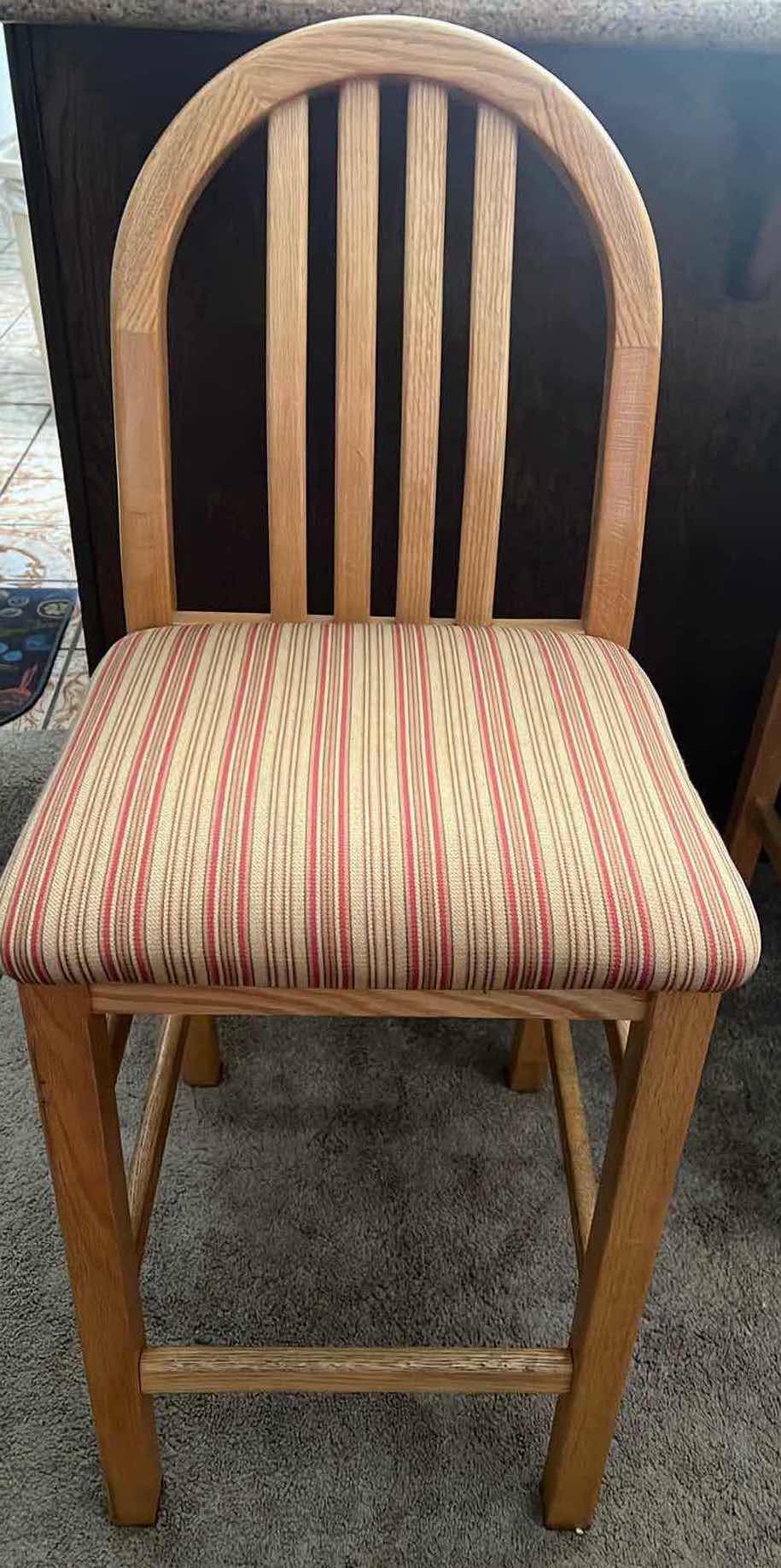 Photo 1 of 24” COUNTER HEIGHT WOODEN BAR STOOLS. TAN AND RED UPHOLSTERED SEAT CUSHIONS.