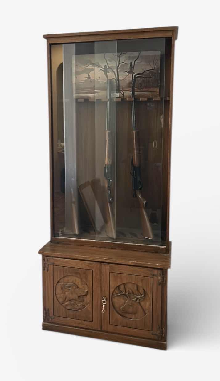 Photo 1 of WOODEN GUN CABINET WITH GLASS FRONT. FEATURES CARVED WOOD DOORS ON LOWER CABINET AND LOCKING STORAGE. DESIGNED TO DISPLAY AND STORE FIREARMS. HOLDS 8, LOWER CABINET 33 1/4 x 16“ x H22“ , TOP CABINET 32“ x 10 1/2“ x H54 1/2“