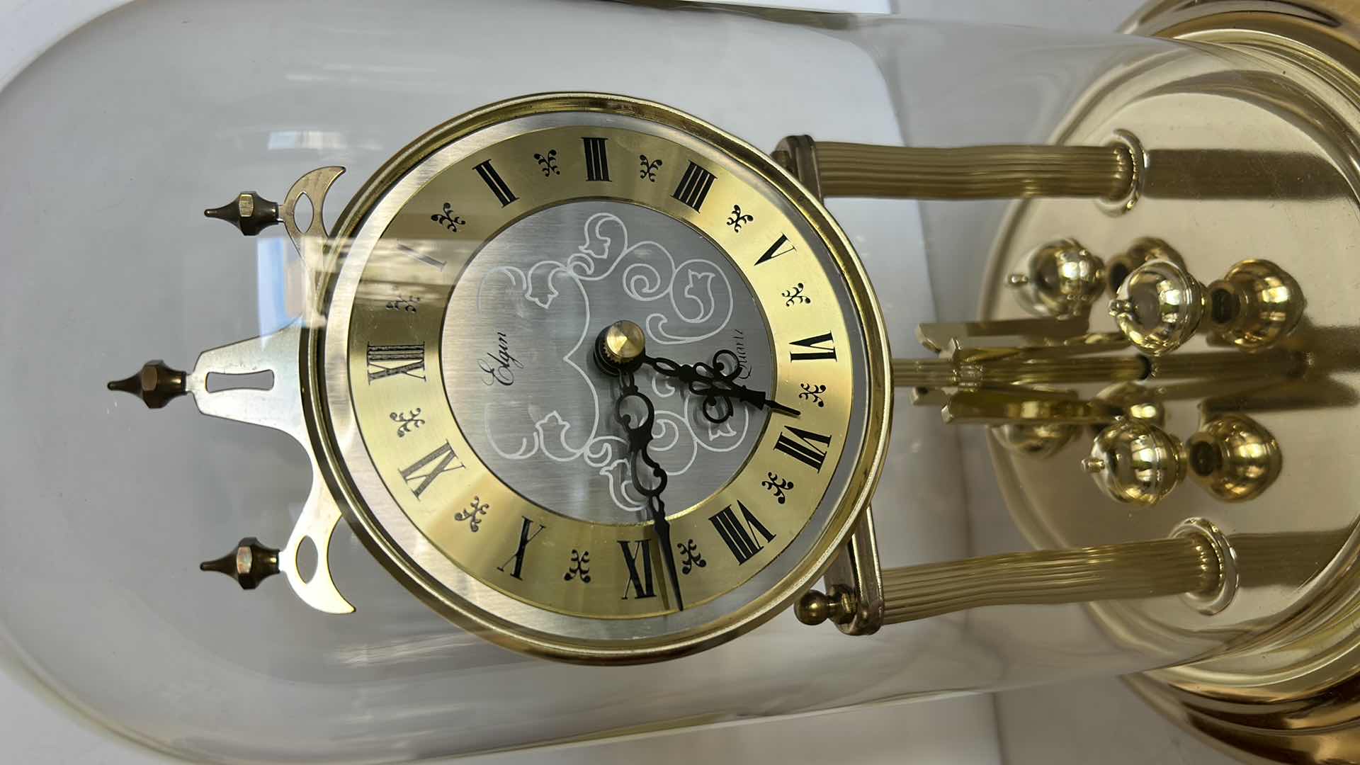 Photo 1 of ELGIN QUARTZ ANNIVERSARY CLOCK WITH GLASS DOME. BRASS-TONE FRAME WITH ROUND CLOCK FACE AND ROTATING PENDULUM BALLS. H12”