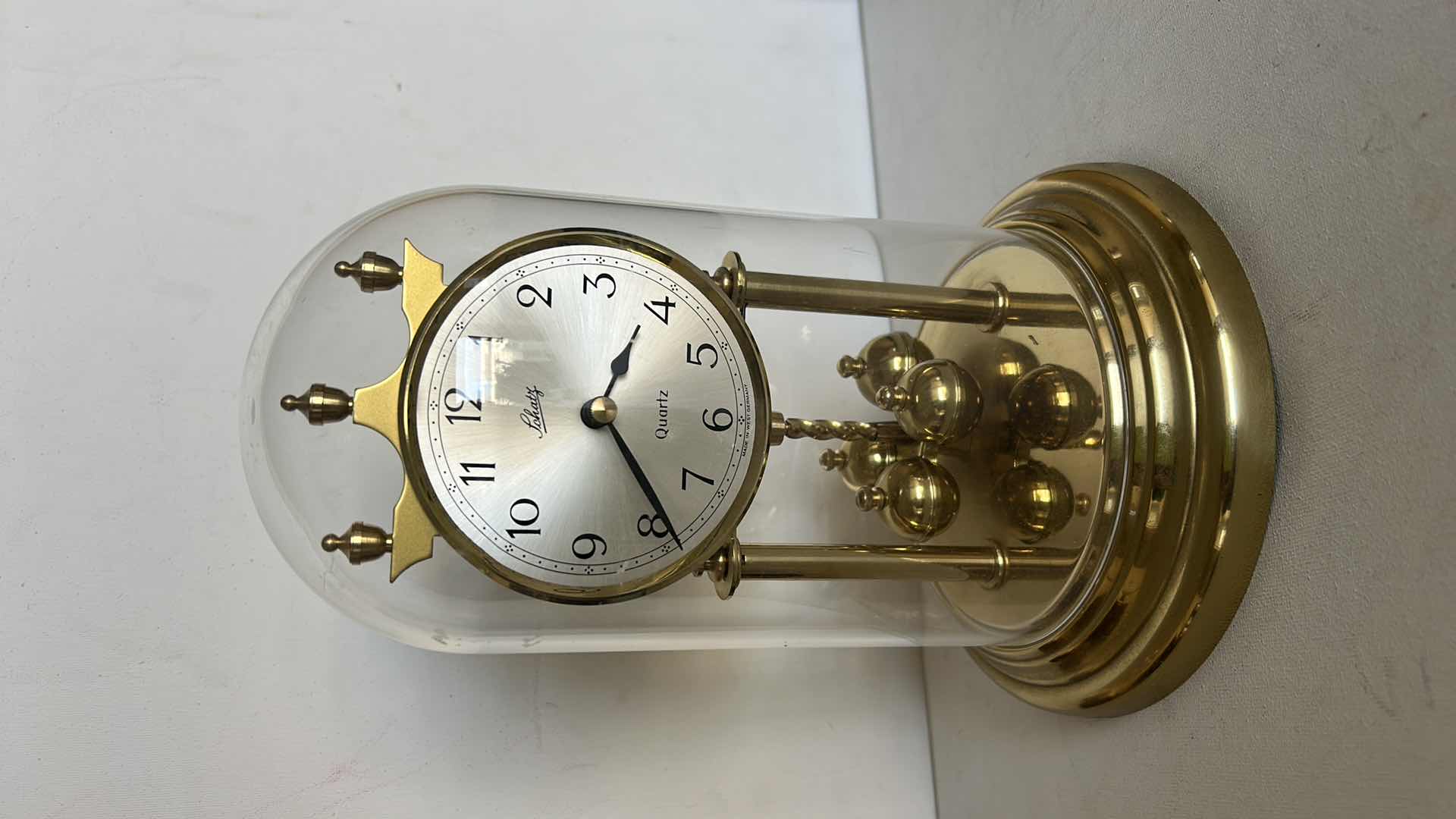 Photo 1 of SCHATZ QUARTZ ANNIVERSARY CLOCK WITH GLASS DOME. BRASS-TONE FRAME WITH ROTATING PENDULUM BALLS AND ROUND CLOCK FACE H 9 1/2”