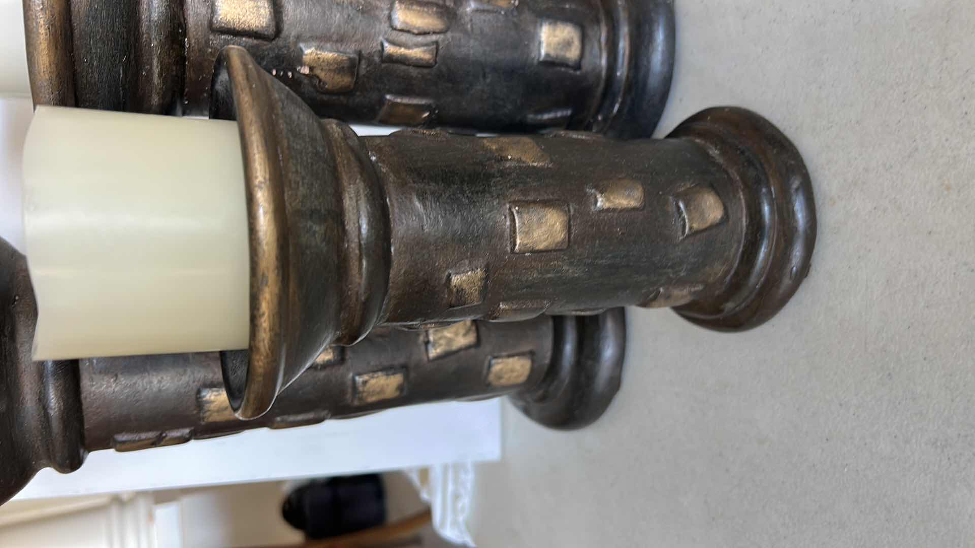 Photo 1 of SET OF THREE DECORATIVE PILLAR CANDLE HOLDERS. MADE OF HEAVY POTTERY WITH A DARK BRONZE-TONE FINISH AND TEXTURED DESIGN. EACH HOLDS A PILLAR-STYLE CANDLE. (TALLEST H13”)