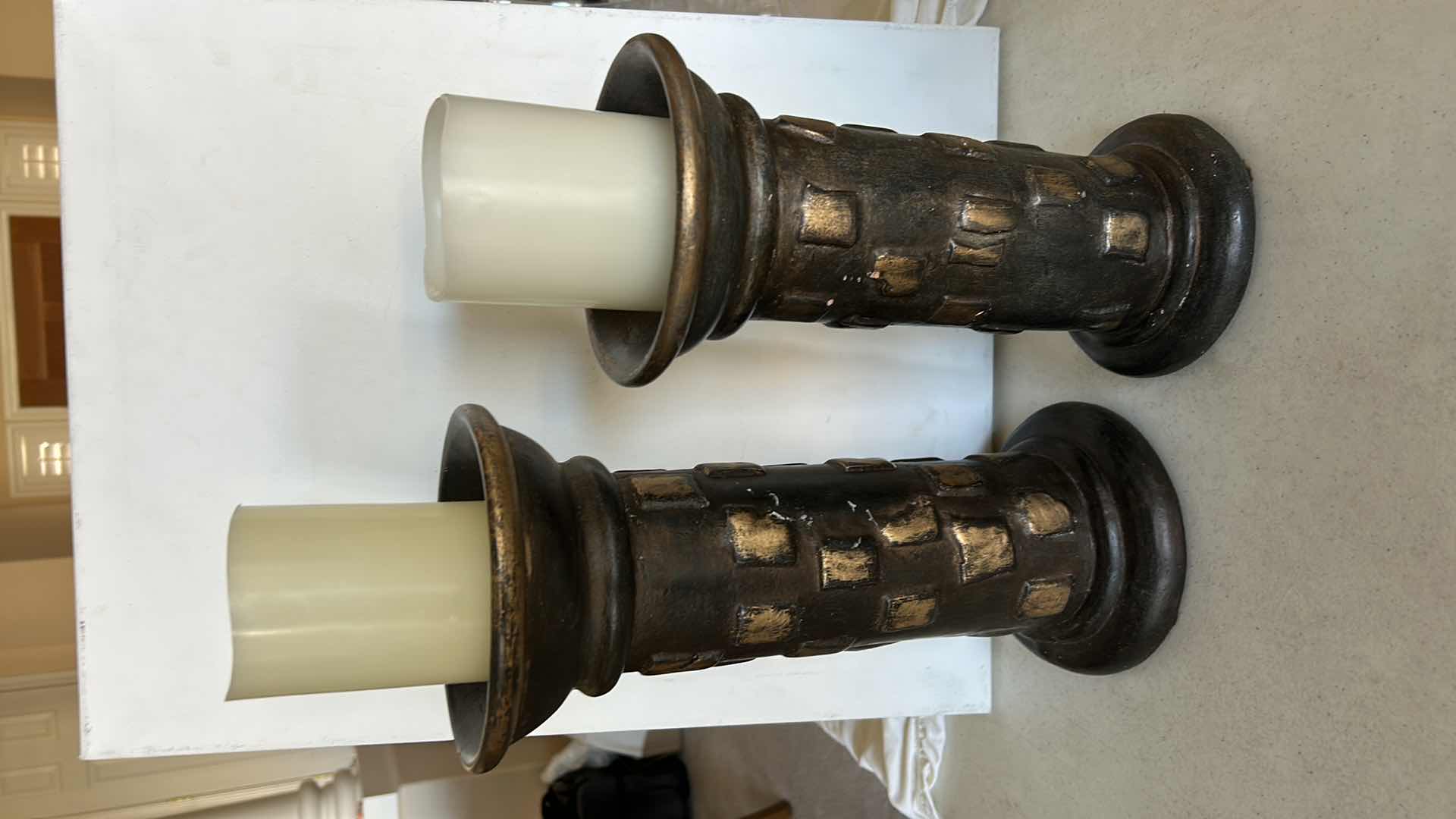 Photo 1 of SET OF THREE DECORATIVE PILLAR CANDLE HOLDERS. MADE OF HEAVY POTTERY WITH A DARK BRONZE-TONE FINISH AND TEXTURED DESIGN. EACH HOLDS A PILLAR-STYLE CANDLE. (TALLEST H13”)