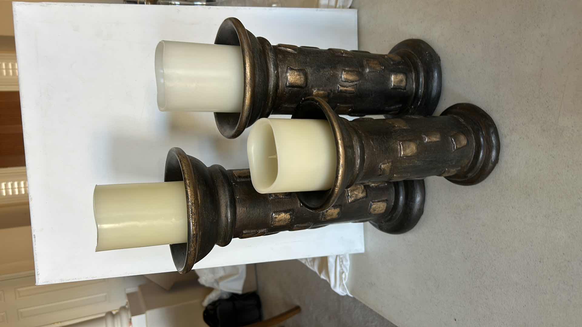 Photo 1 of SET OF THREE DECORATIVE PILLAR CANDLE HOLDERS. MADE OF HEAVY POTTERY WITH A DARK BRONZE-TONE FINISH AND TEXTURED DESIGN. EACH HOLDS A PILLAR-STYLE CANDLE. (TALLEST H13”)
