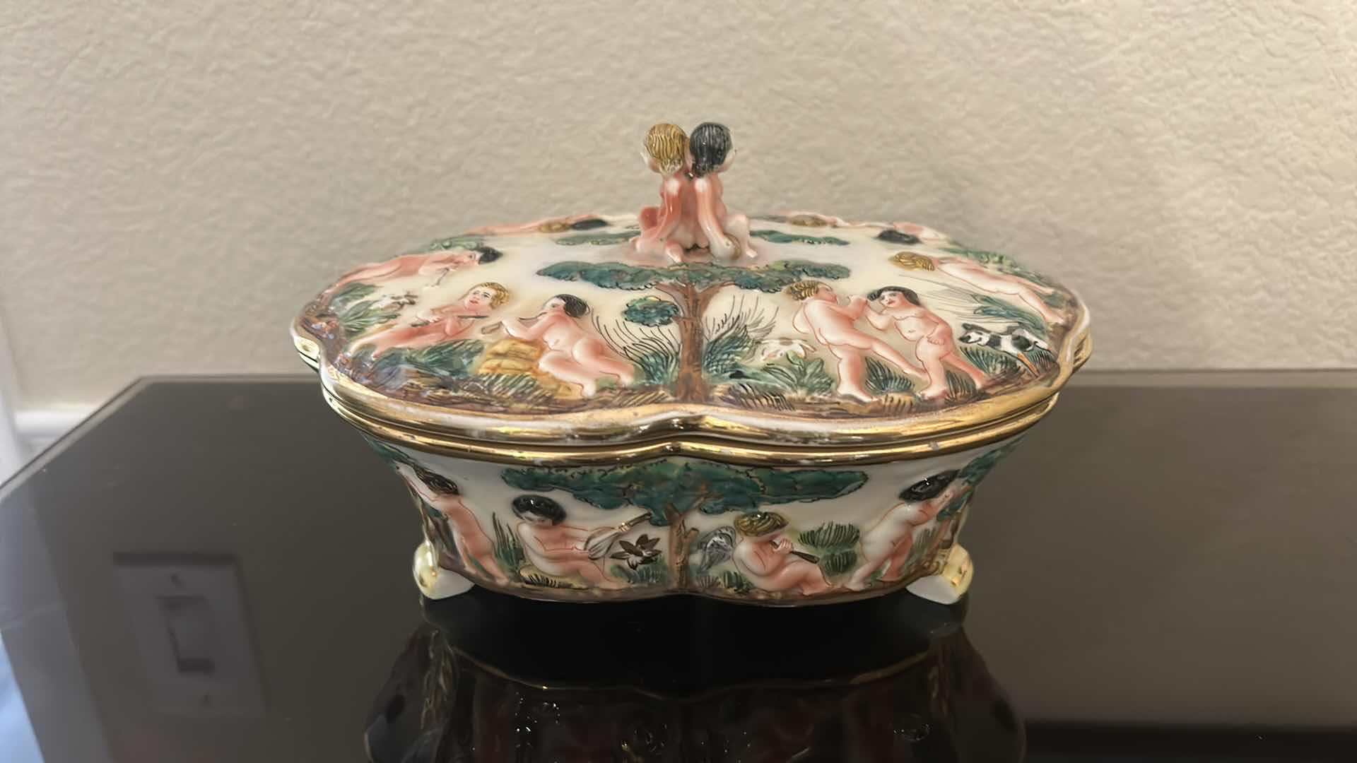 Photo 1 of ANTIQUE CAPODIMONTE ITALIAN PORCELAIN DRESSER SET FEATURING RAISED RELIEF DESIGNS OF CHERUBS .
•THE SET INCLUDES A LARGE LIDDED BOX, A SMALLER LIDDED JEWELRY BOX, AND A SMALL OPEN TRAY. LARGEST 9 1/4” x 7 1/4” x H5 1/2”