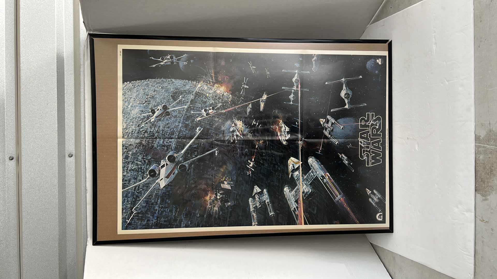 Photo 1 of STAR WARS MOVIE POSTER IN BLACK PLATIC FRAME(22.5”W X 32.5”H) AND STORM TROOPER HELMET HELMET SCHEMATIC IN DARK BROWN WOODEN FRAME(22.5”W X 19”H)