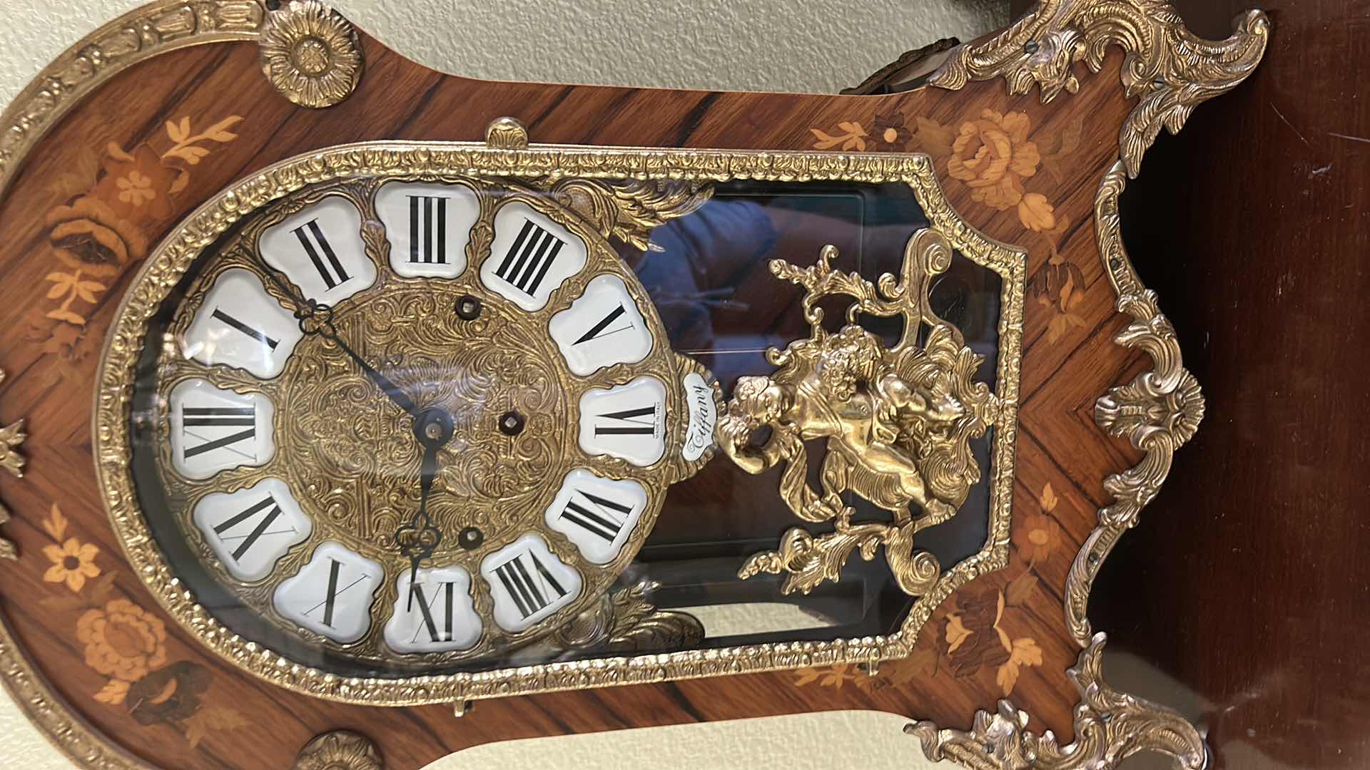 Photo 1 of TIFFANY MADE IN ITALY - FRENCH STYLE VERSAILLES CLOCK FEATURES AN ORNATE GILDED METAL CASE WITH ELABORATE SCROLLWORK, FLORAL MOTIFS, AND A DECORATIVE FINIAL. MATCHING PEDESTAL 14 1/2“ x 6 1/4“ x H31“ PEDESTAL16 1/2” x 9 1/2” x H 44 1/2” TOTAL HEIGHT, INCL