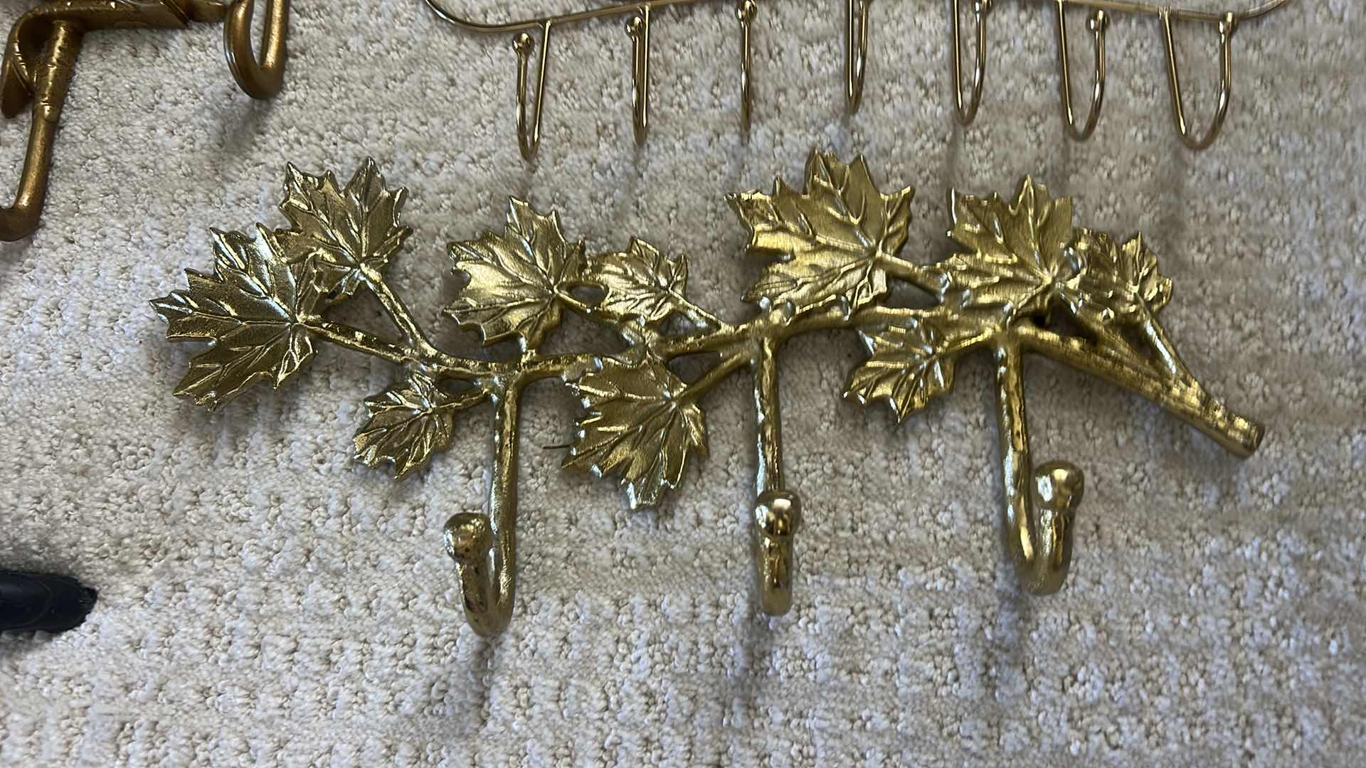 Photo 1 of GOLD-COLORED METAL WALL RACKS FEATURING HOOKS FOR ORGANIZING ITEMS.
