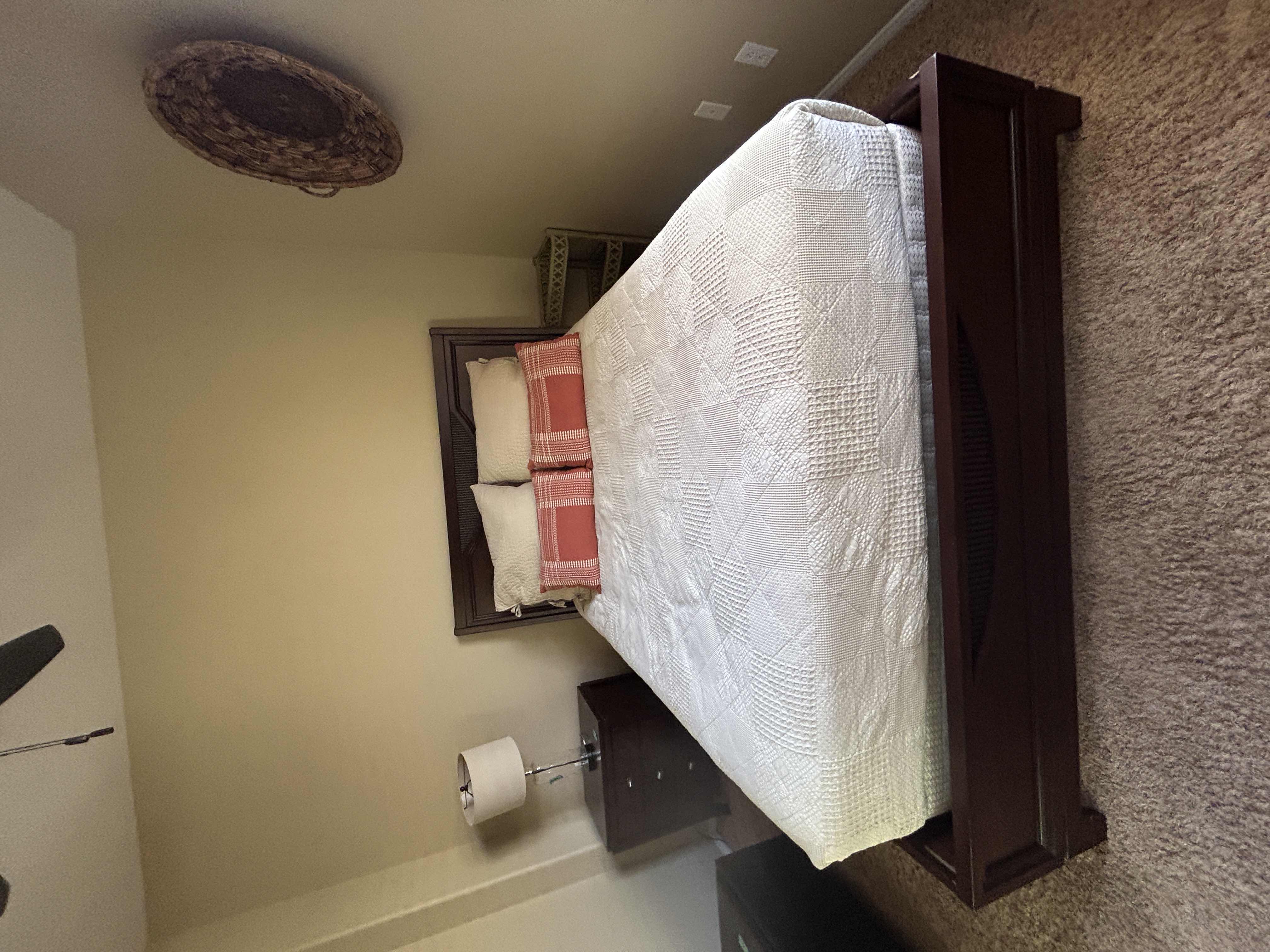 Photo 1 of DARK WOOD PLATFORM BED FEATURING A SLEIGH-STYLE HEADBOARD, MATCHING FOOTBOARD, AND NEUTRAL QUILTED BEDDING WITH ACCENT PILLOWS. INCLUDES SERTA QUEEN MATTRESS. (MATTRESS MEASURES 5 FEET X 81” INCHES HEADBOARD HEIGHT 52 1/2 INCHES)