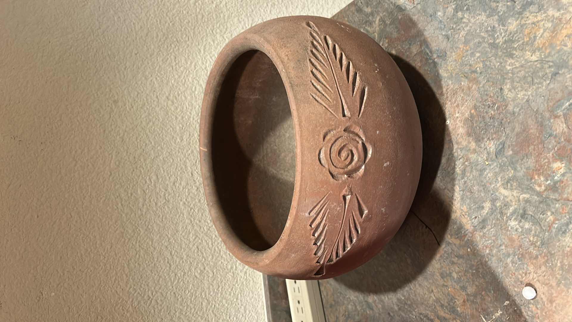 Photo 1 of RUSTICALLY STYLED TERRA COTTA POT FEATURES A HAND-CARVED FLORAL AND LEAF DESIGN. H7.5”