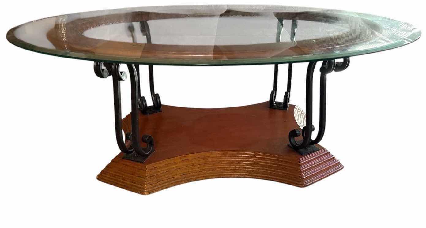 View 1 of OVAL GLASS TOP COFFEE TABLE WITH BROWN WOOD & BLACK METAL SCROLL BASE 51”X36”H18” $200